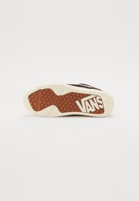 Vans sneaker sole features a textured brown rubber outsole with a white Vans logo and a beige midsole; designed for traction and durability.