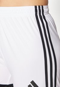 Weiße Sportshorts aus glattem Material mit einem elastischen Bund, verziert mit drei schwarzen vertikalen Streifen an der Seite und Logoodetails.