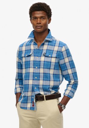 Blauwe en beige geruite shirt met een button-down kraag, twee borstzakken en een logo label op de linkerzak. Gemaakt van katoen, met lange mouwen.