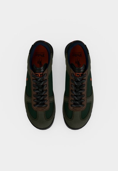 Ζευγάρι πράσινα και καφέ sneakers με κορδόνια, μαύρες σόλες και λογότυπο Polo μέσα στο παπούτσι, εμφανιζόμενα από πάνω σε λευκό φόντο.