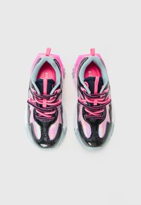 Et par svarte og rosa chunky sneakers med iriserende paneler og lyse rosa snøringer på en hvit bakgrunn.