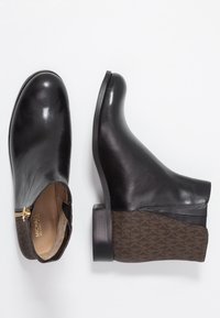 Stivali alla caviglia in pelle nera con punta rotonda, zip laterale e un accento in tessuto marrone a motivo sul tallone. Design con tacco basso a blocco.