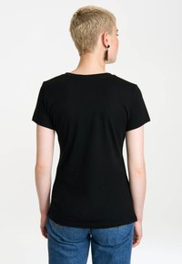 Black short-sleeve t-shirt with a round neckline, fitted shape, and smooth cotton texture, worn with blue jeans, viewed from the back.