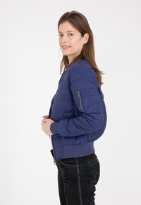 Giubbotto bomber imbottito blu navy con tasca con zip sulla manica sinistra, polsini e orlo a costine. Tessuto morbido e design leggero.