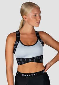 Sujetador deportivo de color azul claro con bandas de acento negro que presentan el texto "MOROTAI". Diseño elegante, tirantes ajustables y una tela suave y elástica.