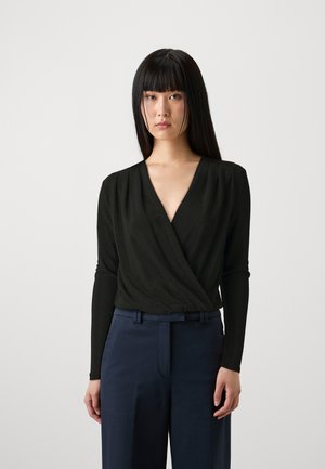 Haut noir à manches longues avec un décolleté en V profond et des détails plissés, associé à un pantalon taille haute bleu marine foncé. Texture de tissu lisse.