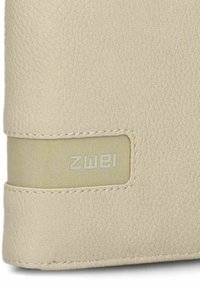 Funda de tableta de cuero beige con superficie texturizada, que presenta una correa suave de color claro y un logotipo de la marca grabado. Costura visible en los bordes.
