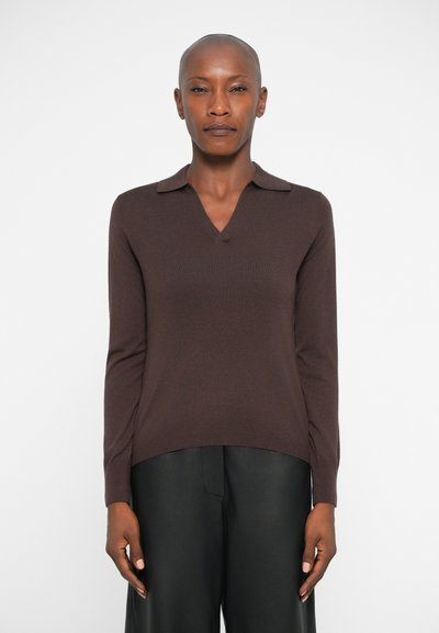 Pull en maille marron avec un col en V et un col, doté de manches longues et d'une coupe décontractée, associé à un pantalon noir. Matériau texturé.