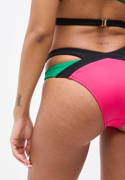 Bikini coloré présentant des panneaux noirs, verts et roses. Texture lisse avec des blocs de couleurs contrastées et un design minimaliste des bretelles.