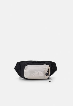Schwarze Bauchtasche mit hellgrauer Fronttasche, Reißverschluss und The North Face Logo auf der Vorderseite, vor schlicht weißem Hintergrund.
