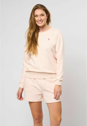 Lichtroze sweatshirt met bijpassende shorts, gemaakt van zachte stof. Beschikt over een ronde halslijn en een klein logo op de borst. Gladde textuur.