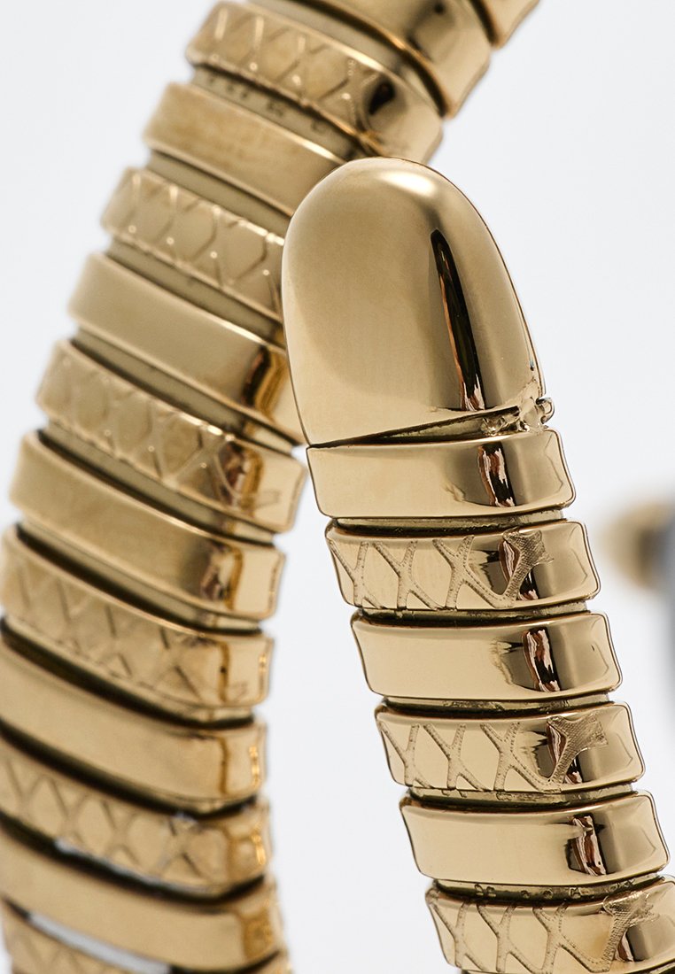 Bracciale dorato con un design flessibile e segmentato caratterizzato da maglie in metallo lucido e testurizzato, concludendosi con un dettaglio di chiusura arrotondato.
