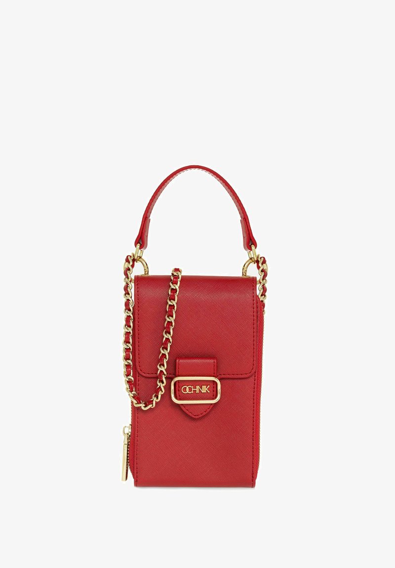 Czerwona torebka z imitacji skóry z złotym łańcuszkiem, prostokątny kształt, z przodu klapa i akcent w postaci logo. Posiada zamek błyskawiczny po stronie.