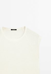 Lyscreme, t-shirt med korte ærmer, rund halsudskæring og blød tekstur. Har raglanærmer og et mærke i nakken bagpå.