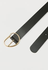 Svart skinnbelte med en gyllen rundet D-formet metallspenne og ett synlig justeringshull på en hvit bakgrunn.