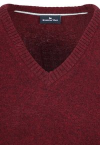 Roter Strickpullover mit V-Ausschnitt. Die Textur ist weich und leicht angeraut, mit einem subtilen Melange-Muster. Markenetikett innen sichtbar.