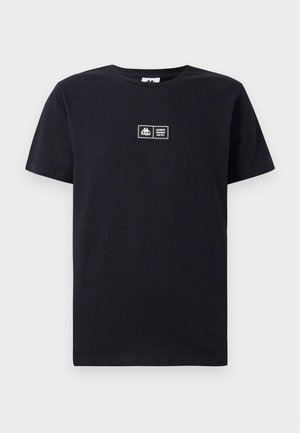 T-shirt en coton noir à manches courtes et col rond. Présente un patch logo à l'avant avec du texte. Design simple et dépouillé.