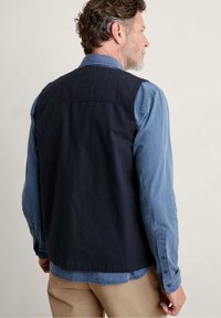 Marinefarbener Stoffwesten über einem hellblau gestreiften Langarmhemd mit geknöpften Manschetten und lockerer Passform; minimalistisches Design.