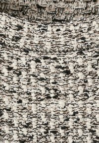 Tekstureret strikstof med en blanding af sorte, hvide og beige garner, der skaber et hævet, løkkeformet mønster.