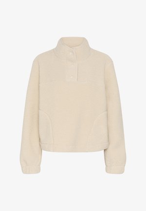 Polaire couleur crème à manches longues, col montant, et trois boutons au niveau de l'encolure, avec des poignets élastiques.