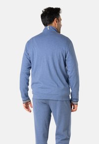 Pull rouge en polaire avec un col montant, doté de poignets rayés. Texture douce, coupe décontractée et design simple. Vue arrière présentée.