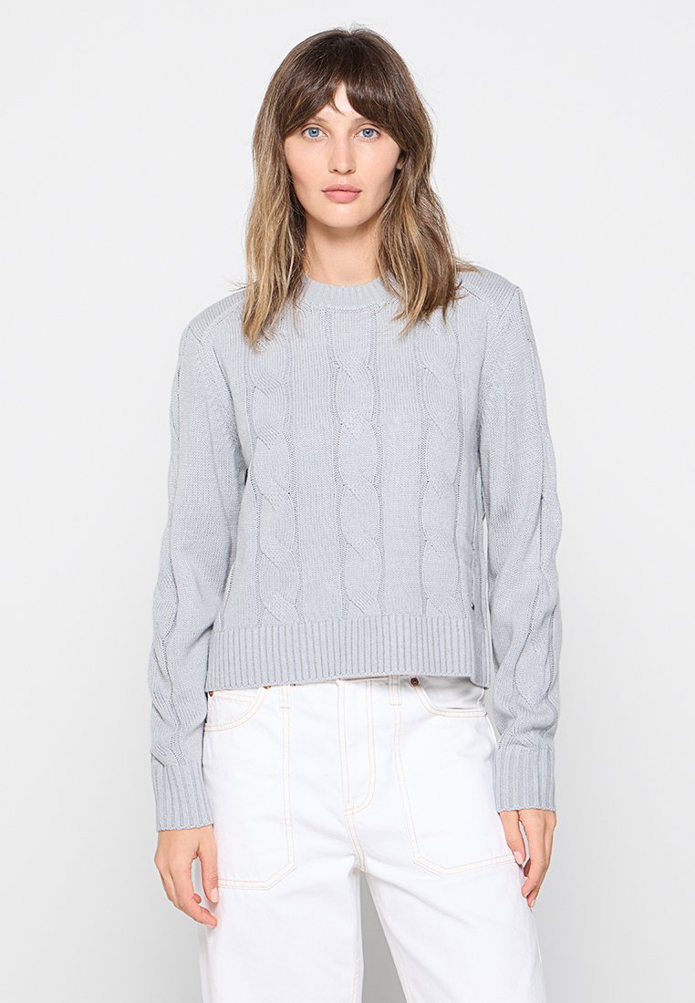 Suéter de punto trenzado gris claro con cuello y dobladillo acanalados, que presenta mangas largas y un diseño recortado. Textura suave.