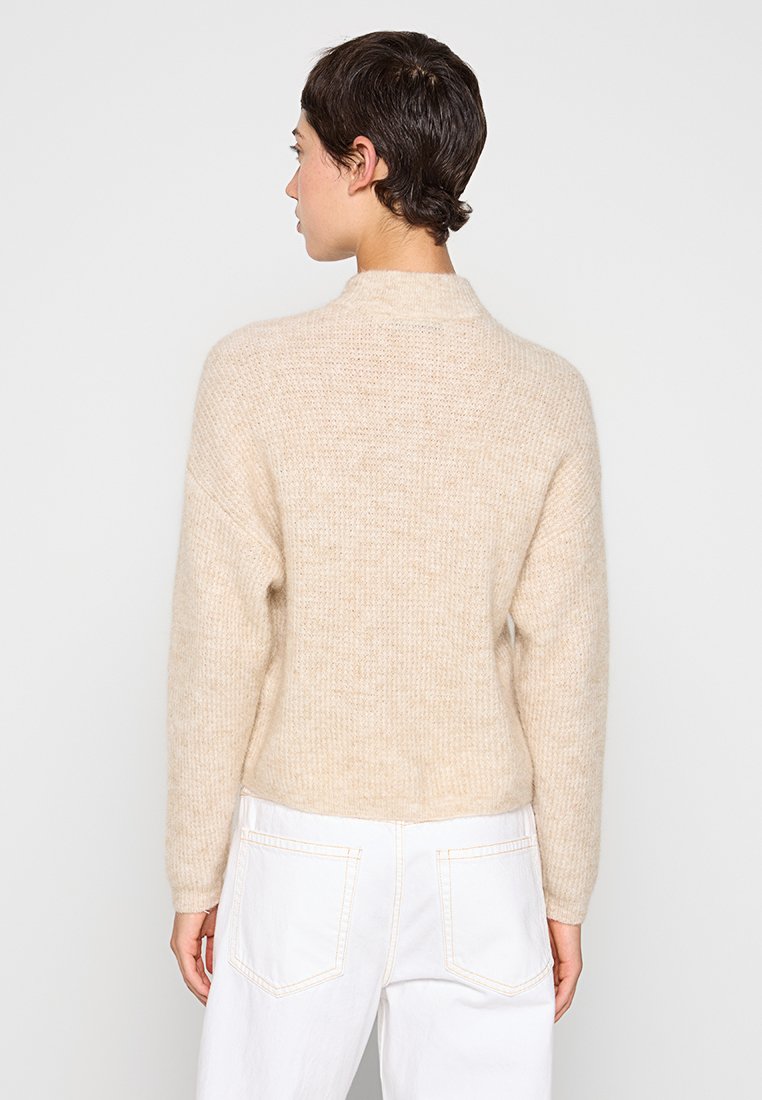 Beige Strickpullover mit langen Ärmeln, Rundhalsausschnitt und strukturiertem Stoff. Das Design zeichnet sich durch eine lockere Passform und dezente Musterung aus.