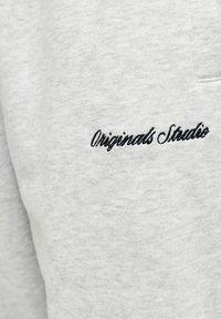 Jasnoszare spodnie dresowe wykonane z mieszanki bawełny, z delikatną teksturą i czarnym, wyszywanym logo "Originals Studio".