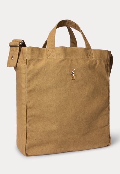 Καφέ τσάντα ώμου από καμβά με κοντά χερούλια και ρυθμιζόμενο λουρί ώμου, με μικρό κέντημα λογότυπο παικτή πόλο στο κέντρο.