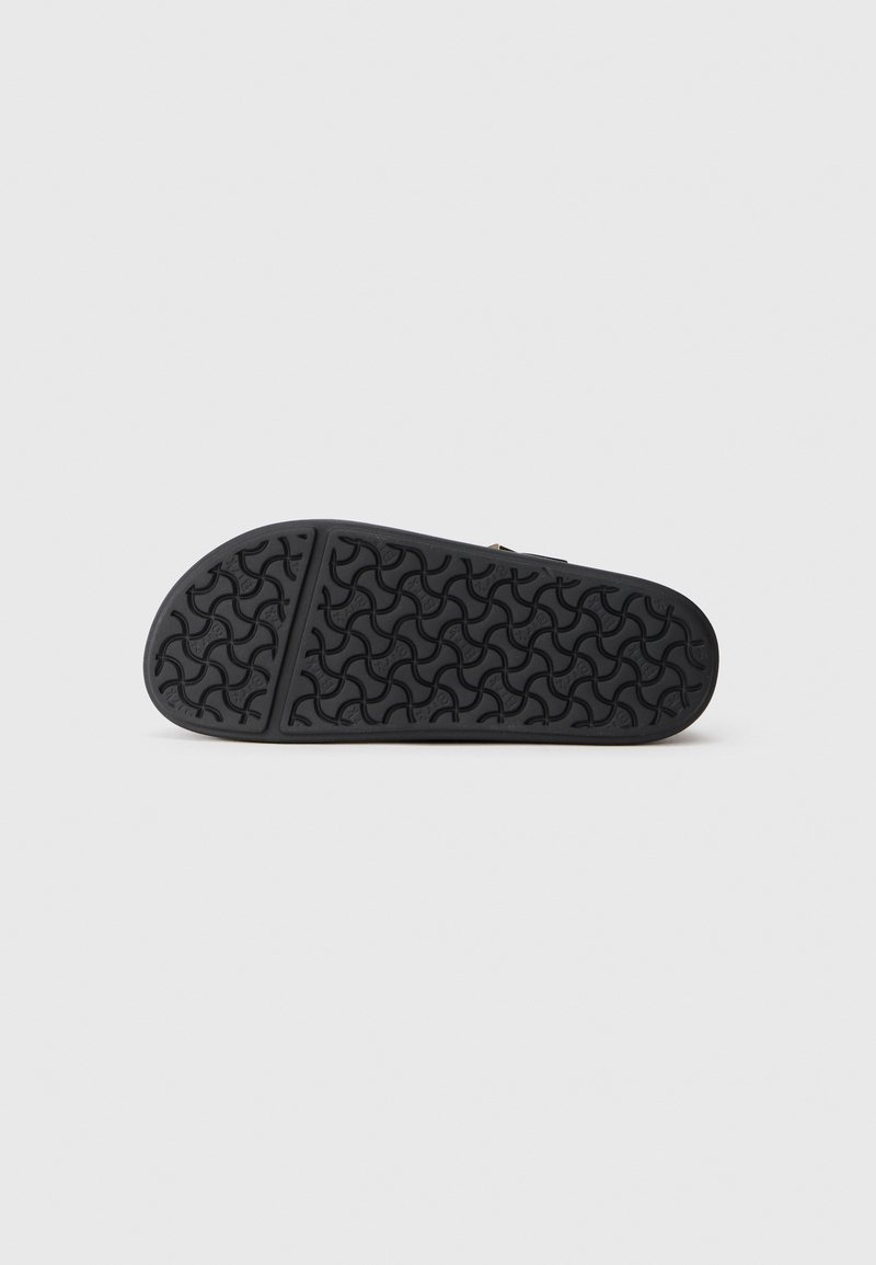 Suela de zapato negra con un patrón de agarre texturizado, que presenta bordes suaves y una forma redondeada. Material de goma duradero para tracción y flexibilidad.