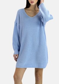 Hellblaues, übergroßes Strickkleid mit tiefem V-Ausschnitt und geripptem Muster. Lange Ärmel und lockere Passform, endet mittelhoch am Oberschenkel.