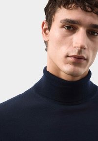 Námořnický rolák vyrobený z hladkého pleteného materiálu, s vysokým límcem a přiléhavým střihem, s jemnými švy.