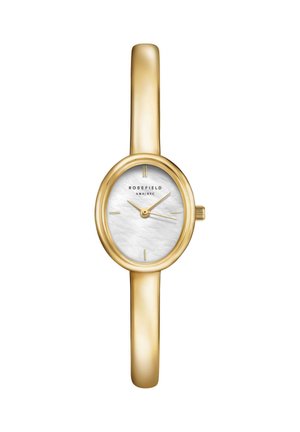 Reloj pulsera delgado tono dorado con esfera ovalada blanca de nácar, marcadores dorados mínimos y tres agujas doradas que indican las 10:10:15.