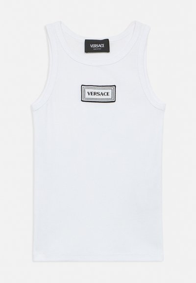 Débardeur blanc sans manches avec un patch rectangulaire du logo Versace bordé de noir centré sur la poitrine et une étiquette noire Versace au niveau du col.