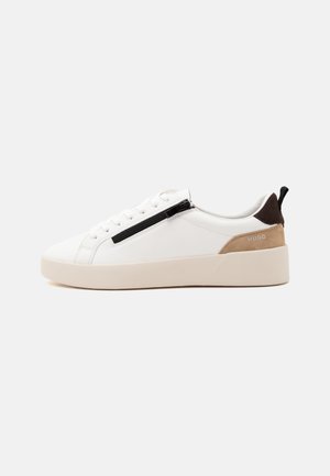 Baskets blanches basses avec semelle beige, fermeture éclair noire sur le côté, partie talon en daim marron clair, languette de talon noire et logo "HUGO".