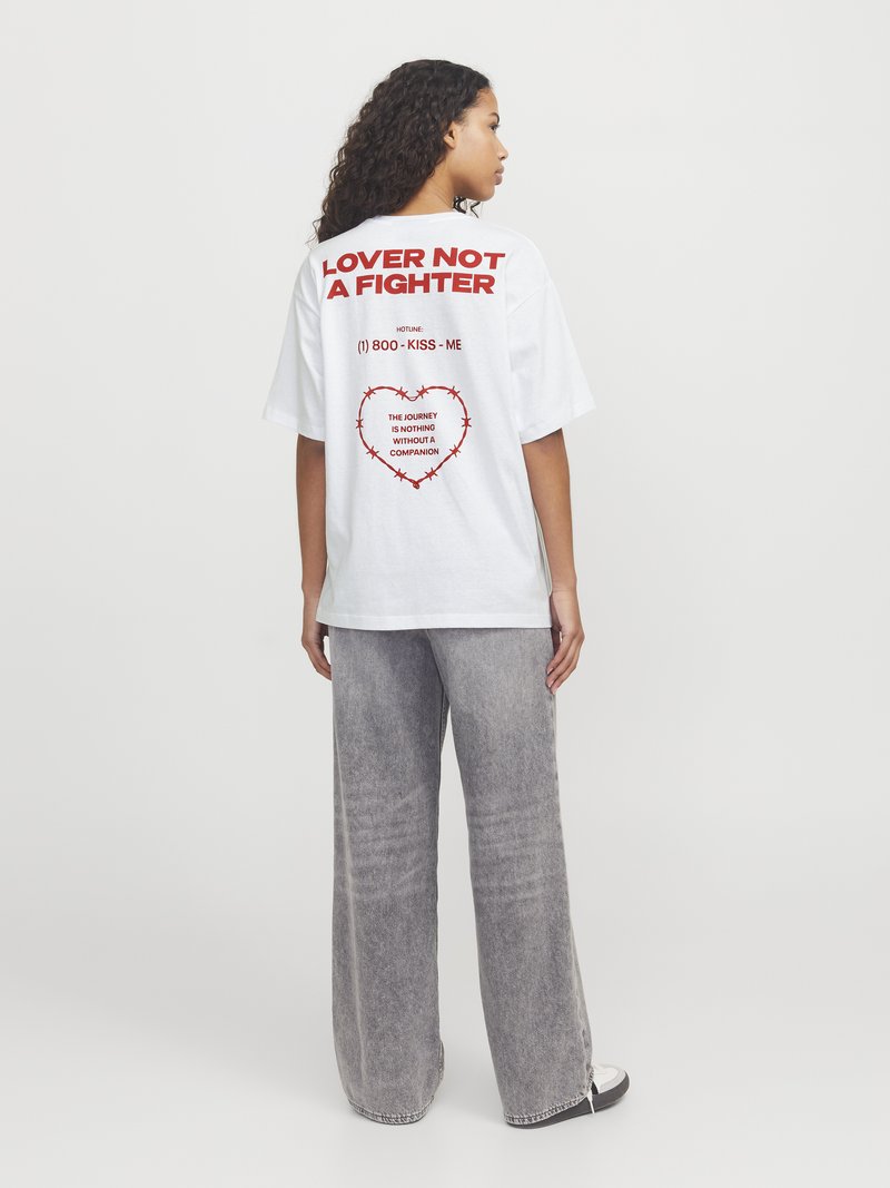 Hvit oversized t-skjorte med rød tekst "LOVER NOT A FIGHTER" og grafisk hjerte, sammen med grå vide bukser, minimalistisk design.