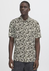 Short-sleeve shirt in cream with a black leafy pattern. Cotton material, button-down collar, and chest pocket detail.
