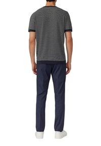 Koszulka w paski w kolorze granatowym i białym z krótkim rękawem, połączona z ciemnoniebieskimi spodniami i białymi sneakersami. Prosty design, casualowy krój.