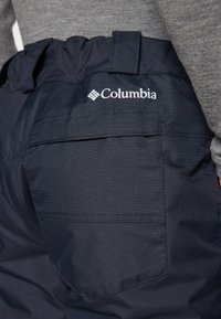 Jūros mėlynumo Columbia kelnės iš švelnaus, tekstūruoto audinio. Yra surinkta juosmens linija ir gale kišenė su logo detalė viršuje.