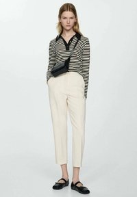 Top de manga larga a rayas en blanco y negro, pantalones crema ajustados, bolso cruzado negro y bailarinas negras. Tejidos suaves y diseño ajustado.