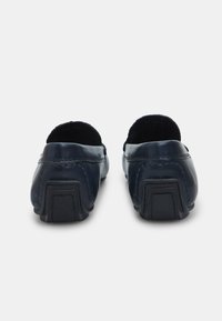 Loaferi din piele maro închis, cu un finisaj neted, toc mic și vârf rotund; detalii de cusătură pe părți, talpă din cauciuc robustă.