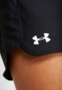 Svarta träningstights i stretchmaterial med en slät yta, med en vit Under Armour-logotyp och en böjd nederkant.