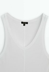 Débardeur blanc avec un col en V, fabriqué dans un tissu lisse et léger. Présente des coutures minimales et une étiquette noire au niveau du col.