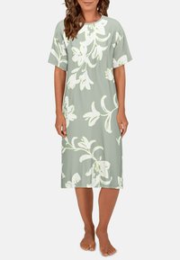 Camicia da notte floreale in verde pastello con grandi motivi floreali bianchi. Maniche corte e vestibilità ampia, realizzata in tessuto leggero.