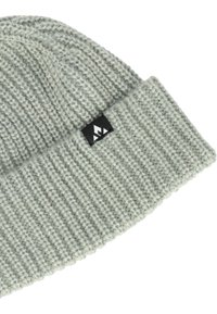 Grå stickad beanie med ribbat mönster, med en vikt kant och en svart etikett med en logotyp.