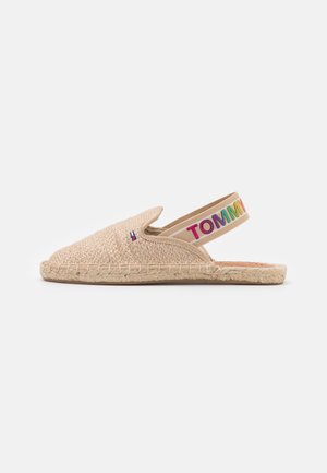 Espadrille beige avec une texture tissée, un bout pointu et un design à bride arrière. Présente une bande colorée "TOMMY" au talon. Semelle en jute naturel.