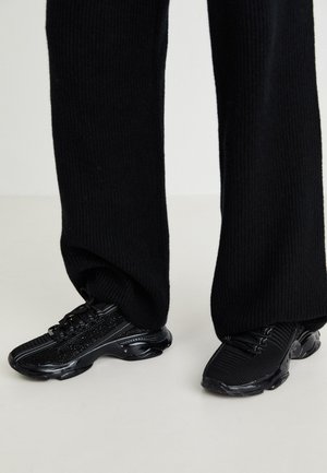 Sneaker nere con tomaia in maglia testurizzata, forma elegante e suola nera lucida, dotate di sottili dettagli riflettenti e design con lacci.