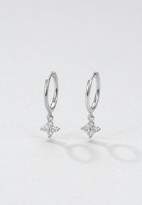 Orecchini a cerchio in argento con un ciondolo a forma di stella decorato con piccole pietre bianche. Superficie liscia con una finitura lucida.