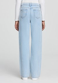 Jasnoniebieskie dżinsy o szerokich nogawkach z wysokim stanem, dwoma tylnymi kieszeniami i czystym wykończeniem. Wykonane z denimu o gładkiej fakturze.