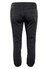 Svarta byxor med slim fit, med sömnadsdetaljer, två bakfickor och en slät textur. Sömmarna går längs sidorna.